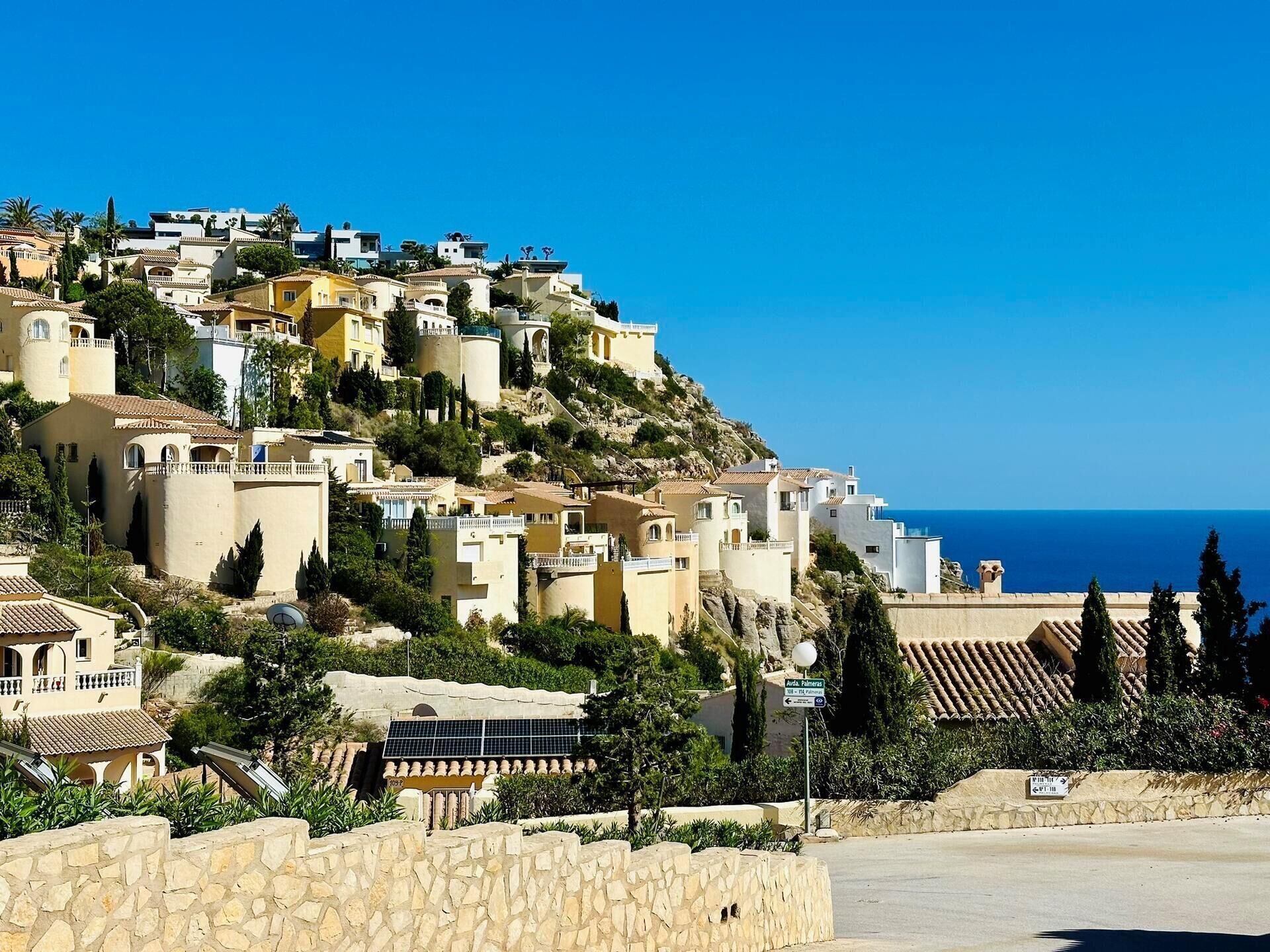 A coastal village with terraced houses, a clear blue sky, and a view of the sea.