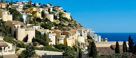 A coastal village with terraced houses, a clear blue sky, and a view of the sea.
