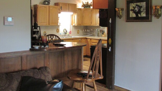 Una cocina con armarios de madera, un comedor con sofá de cuero y un ventilador de techo.