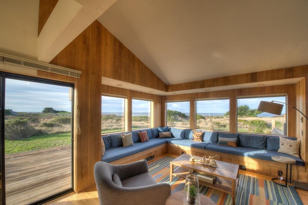 Un interior moderno con un gran panel de madera en la pared, un sofá modular y vistas al exterior.