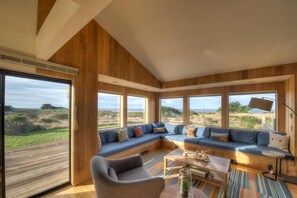 A modern interior with a large wooden panel wall, a sectional sofa, and a view of the outdoors.