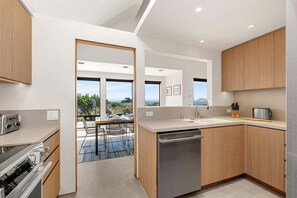 A modern kitchen with a dishwasher, a built-in oven, and a dining area with a view.