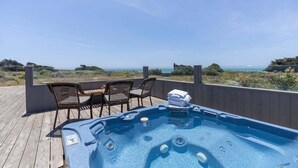 Un bain à remous sur une terrasse en bois, avec vue sur l’océan.