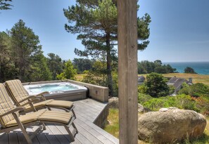 A wooden deck with a hot tub and lounge chairs overlooking a scenic ocean view. - This beautifully appointed home provides spectacular white water ocean views (Sea Ranch)