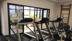 Un gimnasio con cintas de correr, un banco de pesas y una máquina de remo.