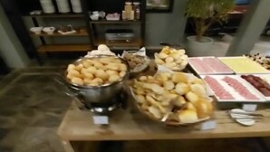 Una mesa de buffet con diversos alimentos, incluyendo pan, pasteles y carnes.
