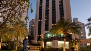 Un edificio de hotel alto con varios pisos, rodeado de palmeras y senderos bien iluminados.