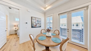 A dining area with a round wooden table, four chairs, and a vase with flowers.