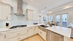 A modern kitchen with white cabinetry, a stainless steel sink, and a built-in dishwasher.
