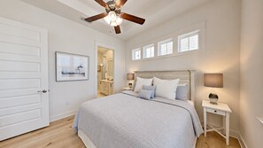 A bedroom with a bed, bedside tables, a ceiling fan, and a window with blinds.
