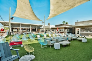 An outdoor seating area with various chairs and tables, a grassy lawn, and a building with signage.