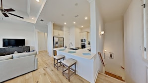 A modern kitchen with a central island, a dining area with a sofa, and a TV.