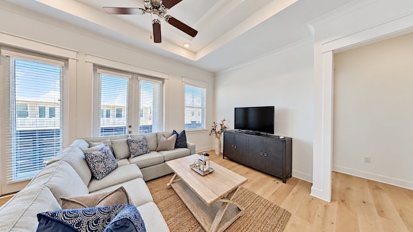 A modern living room with a sectional sofa, a flat-screen TV, and a wooden coffee table.