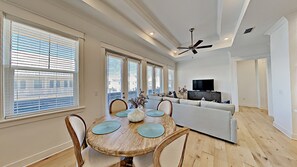 A spacious living room with a dining area, a sofa, a television, and a ceiling fan. - "Settle By The Sea" - Prominence- Sleeps 6 (Inlet Beach)