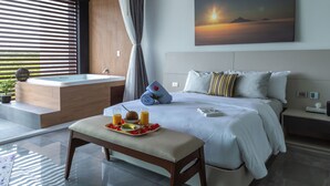 A modern hotel room with a large bed, a sitting area with a tray of breakfast, a bathtub, and a painting of a sunset. - Solmare Apartments & Suites (Akumal)
