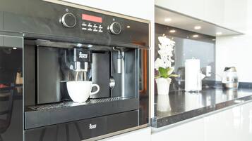 Una cucina moderna con macchina per espresso integrata, una tazza bianca e una pianta in vaso.