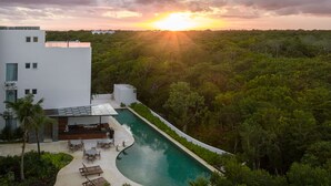 A modern building with a swimming pool surrounded by lush greenery. - Solmare Apartments & Suites (Akumal)