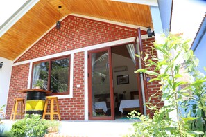 A brick house with large sliding glass doors, wooden steps, and a small porch area. - Phong Nha Friendly Home 2 (Bo Trach)
