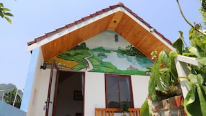 A building with a sloped roof, a wooden bench outside, and a mural on the wall. - Phong Nha Friendly Home 2 (Phong Nha)