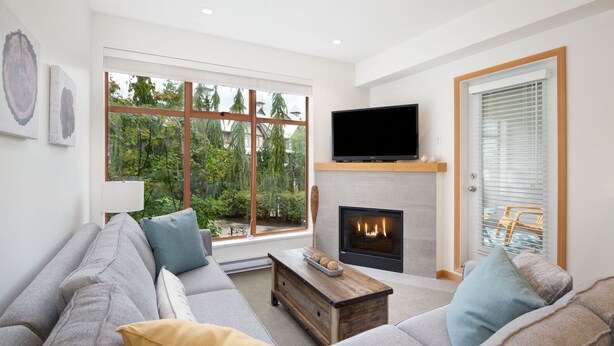 Una sala de estar moderna con chimenea, un ventanal grande y un televisor.