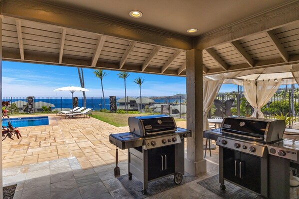 An outdoor patio with two gas grills, a pool, and a view of the ocean. - Molokai views, refreshed upgrades, relax comfort (Lahaina)