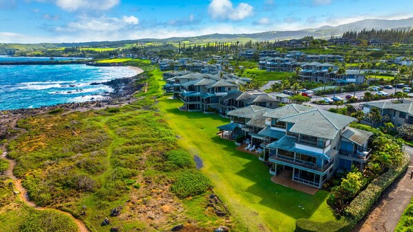 A coastal residential area with houses, a beach, and a mountainous backdrop. - Molokai views, refreshed upgrades, relax comfort (Lahaina)