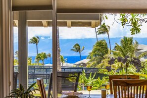 A dining area with a view of the ocean and palm trees. - Molokai views, refreshed upgrades, relax comfort (Lahaina)