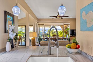 A modern kitchen with a marble countertop, a stainless steel faucet, and a bowl of fruit. - Molokai views, refreshed upgrades, relax comfort (Lahaina)