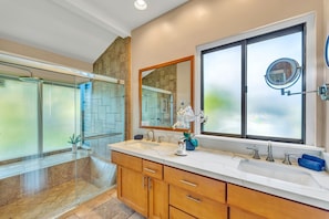 Un baño moderno con un espejo grande, dos lavamanos y una zona de ducha.
