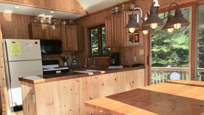 A wooden kitchen with a central island, a refrigerator, a microwave, and a coffee maker.