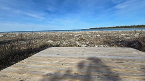 A wooden deck leading to a rocky shoreline with a clear sky.