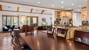 A spacious kitchen with wooden cabinets, a dining area with a large table and chairs, and a view of the outdoors through large windows.
