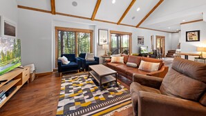 A spacious living room with wooden beams, a large TV, and a fireplace.