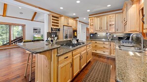 A spacious kitchen with wooden cabinets, granite countertops, and stainless steel appliances.