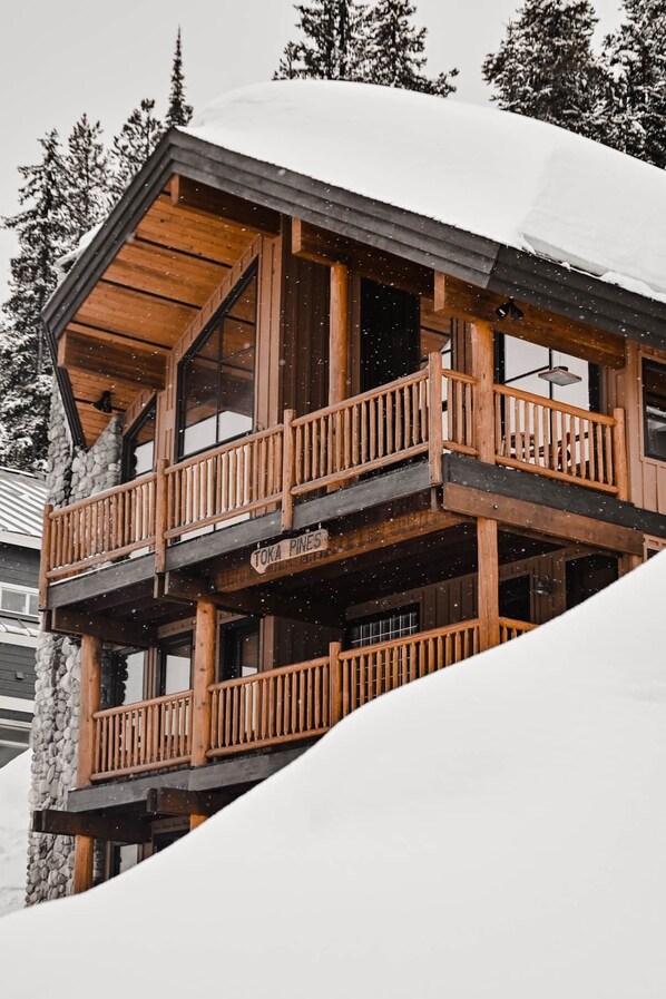 Una cabaña de madera con balcón, rodeada de nieve.