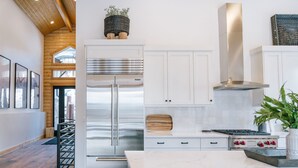 Une cuisine moderne dotée d’un réfrigérateur en acier inoxydable, de meubles en bois et d’un plan de travail en marbre.