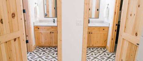 Ein Badezimmer mit Holzausstattung, zwei Waschbecken und einem gemusterten Boden.