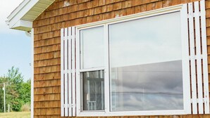 Una casa de madera con un ventanal grande y detalles blancos.