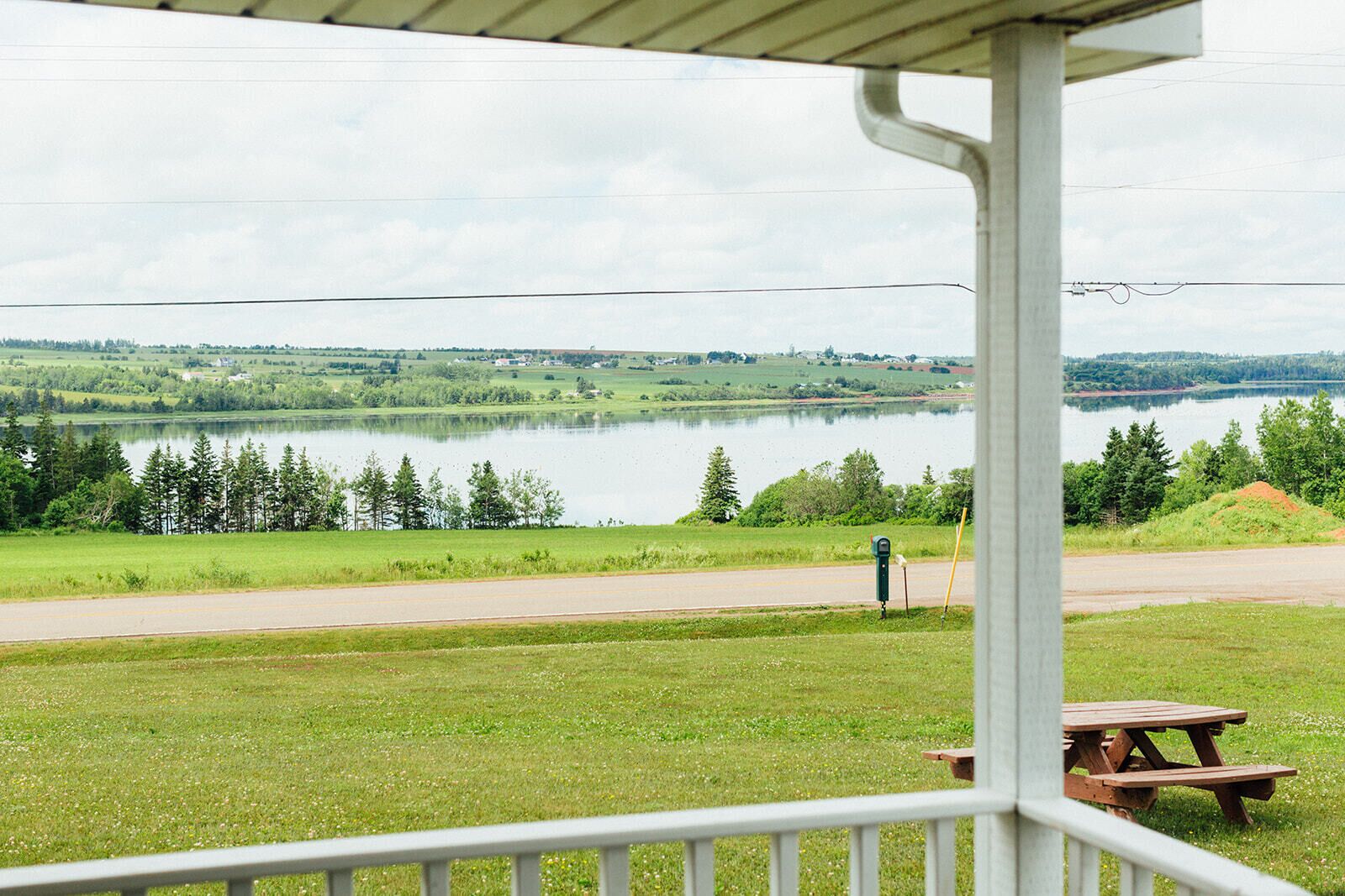 Une vue sur le lac depuis une véranda abritée, avec une table de pique-nique et une boîte aux lettres.