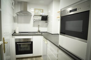 A modern kitchen with white cabinetry, stainless steel appliances, and a black oven. - MADRID. C30 VacaHome Management (Madrid)