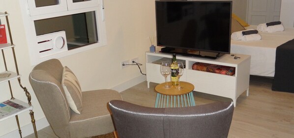 A living room with a TV, a sofa, a small table with wine glasses, and a bed in the background. - MADRID. C30 VacaHome Management (Madrid)