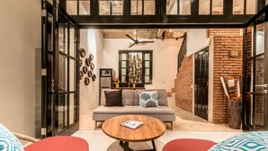 A modern living room with a sofa, a coffee table, and two red chairs. - Central 1 Bedroom Villa 5 min walk to Seminyak Beach (Seminyak)
