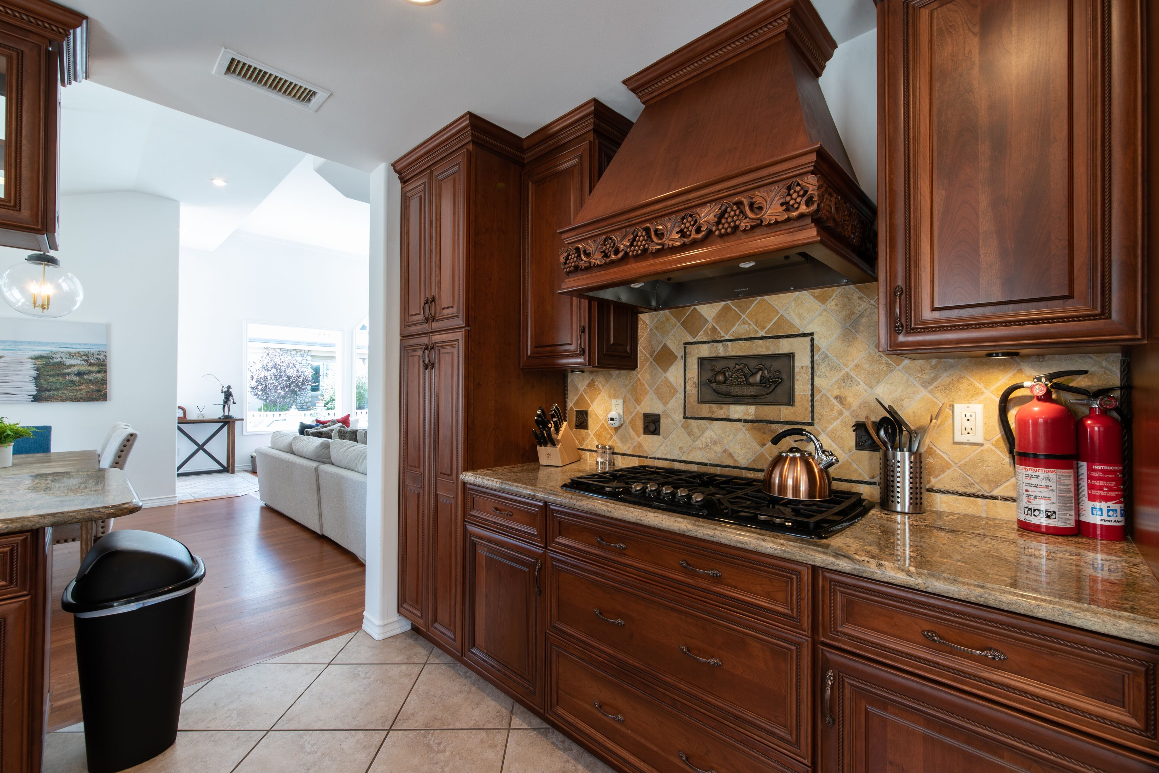 A kitchen with wooden cabinets, a gas stove, and a tiled backsplash.