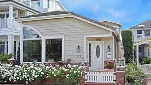 Een tweelaags huis met een veranda, grote ramen en een witte picket fence.