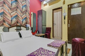 Una habitación de hotel con una cama, un escritorio, una silla, un armario y una puerta.