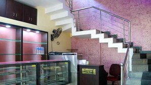 Una zona de recepción con mostrador de información, una escalera y un ventilador en la pared.