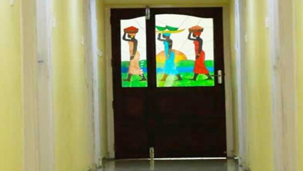 Un pasillo con una puerta doble que presenta coloridas ilustraciones de figuras cargando objetos.