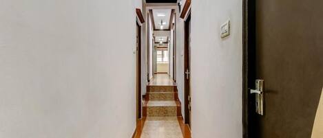 A hallway with a tiled floor, wooden trim, and doors on either side.