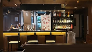 A bar area with a counter, hanging lights, and shelves of bottles. - Vinary Hotel (Bangkok)