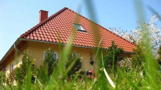 A house with a red-tiled roof, surrounded by greenery. - Morning sun - Apartments Meeresfrische (Kühlungsborn)